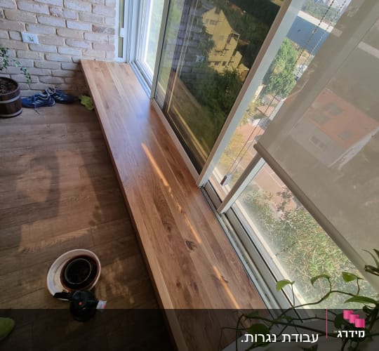 מדף עץ רחב ליד חלון גדול